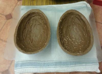 Photo of two giant egg moulds coated in a thick layer of solid chocolate, with the edges flattened