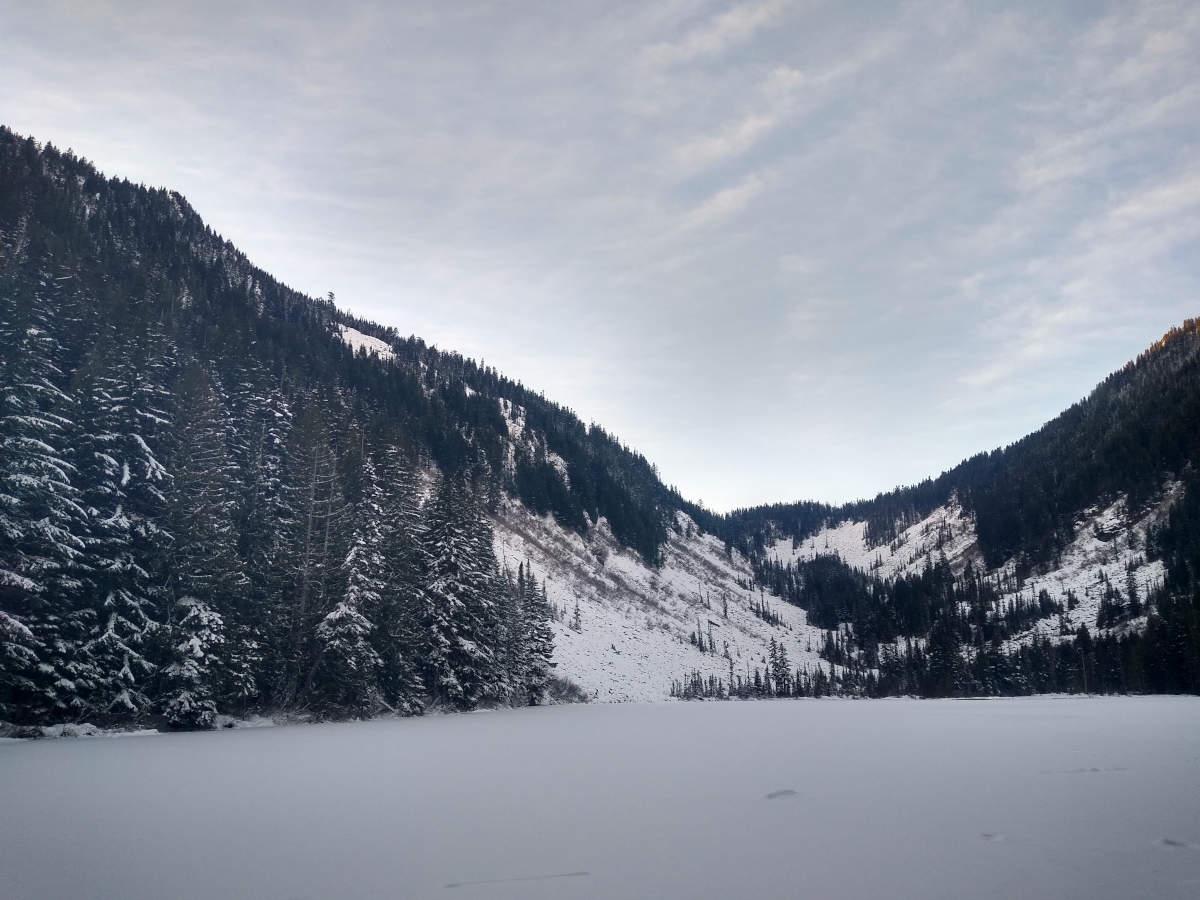 A frozen lake with snowy valley on the other side.