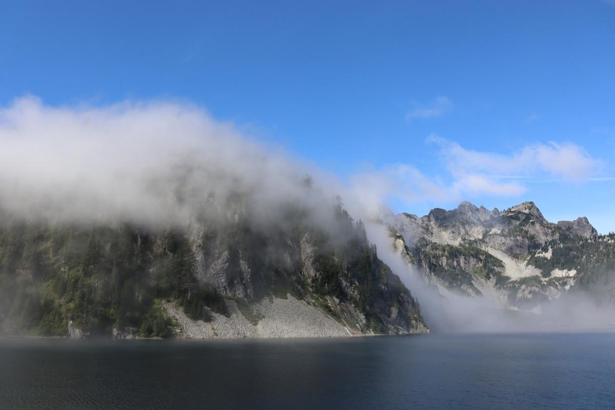 View across the lake of mist rolling up the mountainside.