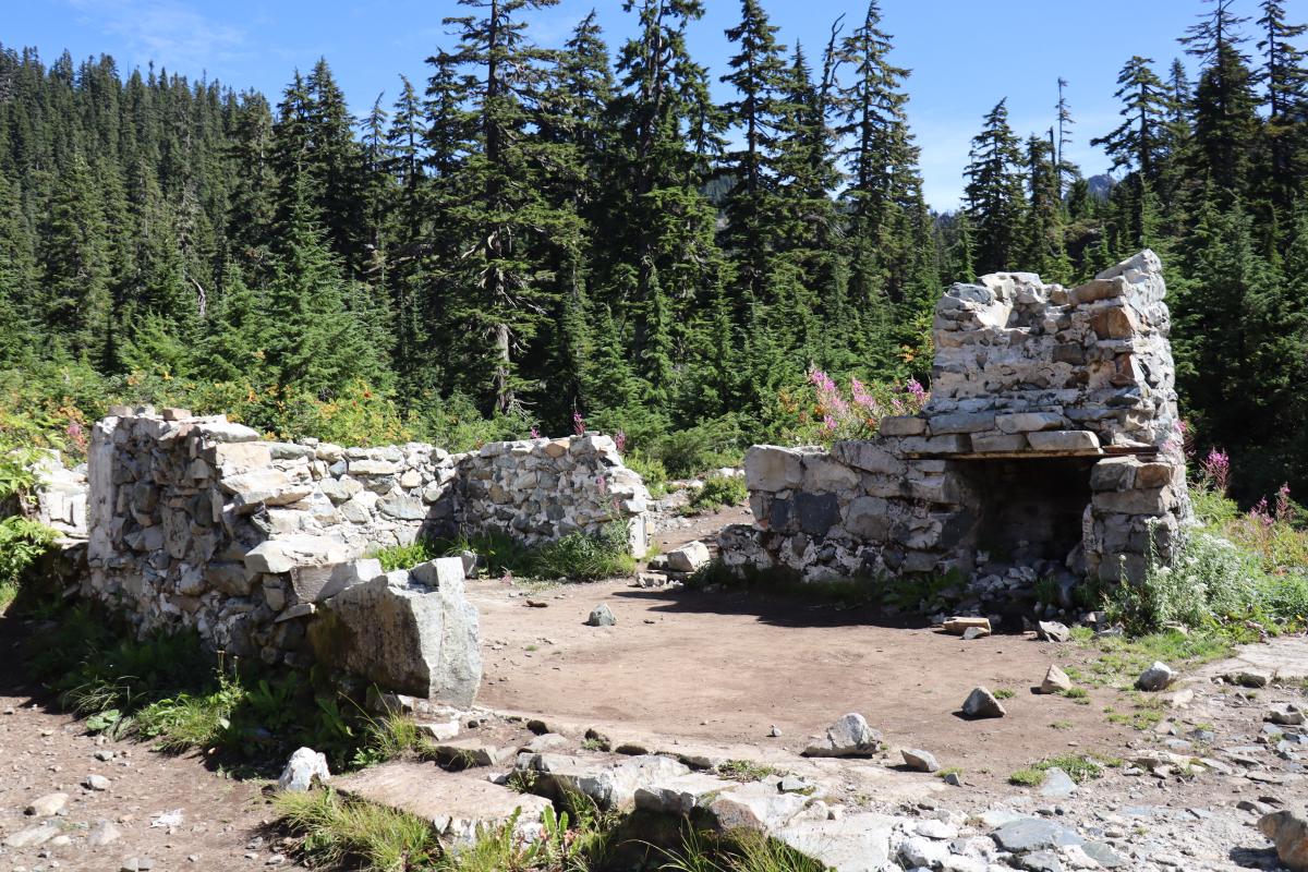 Some ruins, consisting of a rectangle footprint of a single room, with three walls of stone about knee height, and one wall with a stone fireplace about chest height.