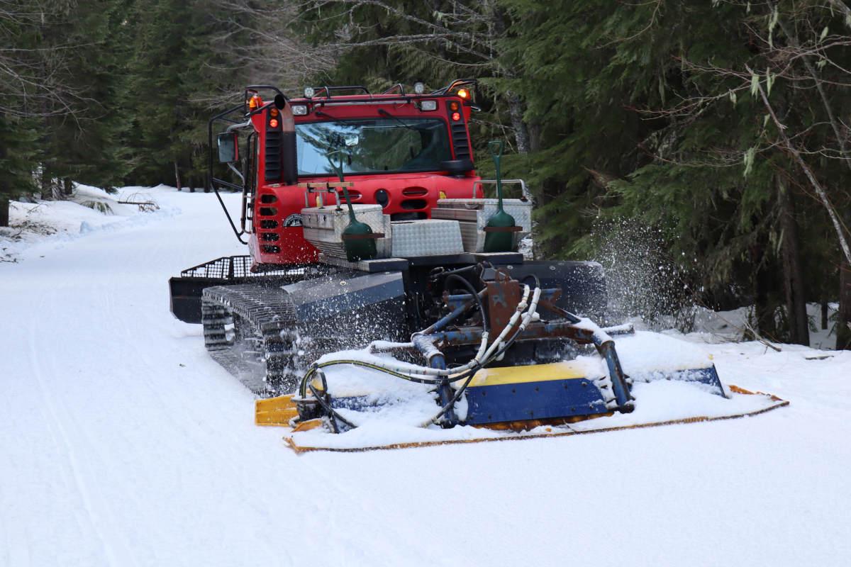 A red snowcat grooming the snow.