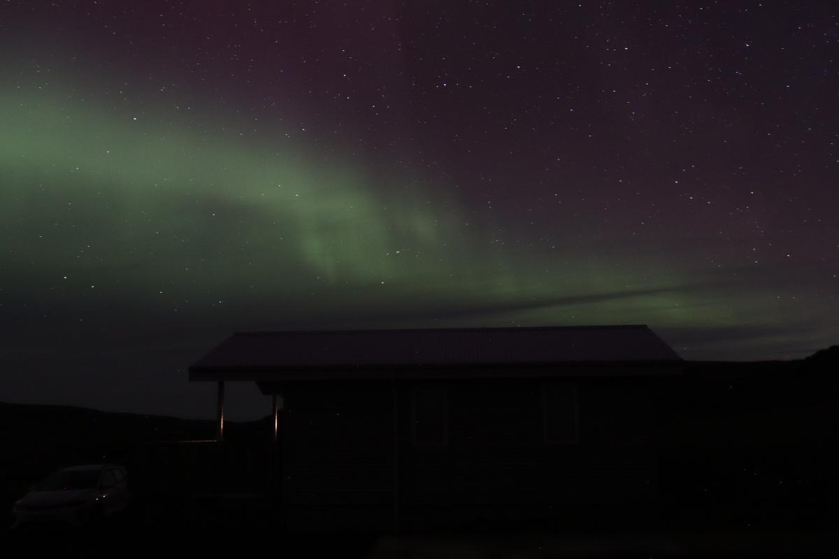 Photo of green aurora over cabin.