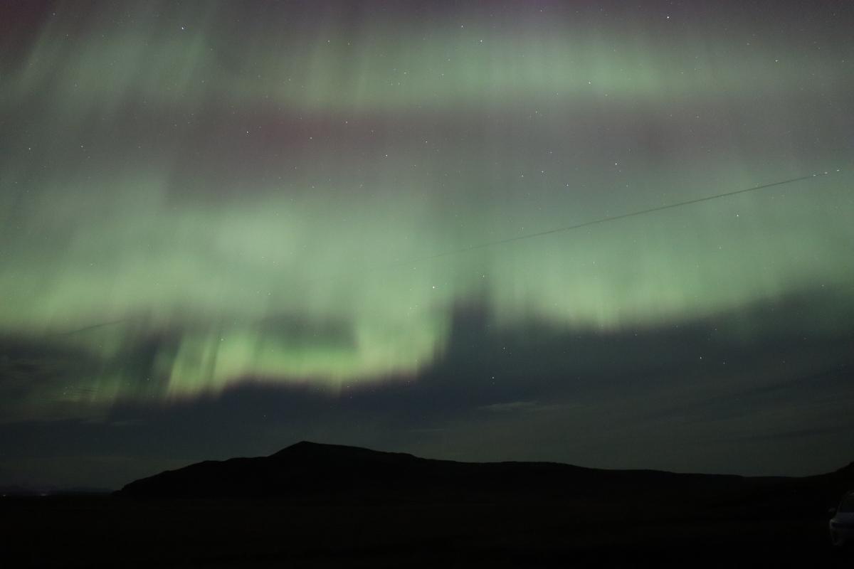 Photo of green aurora over mountains.