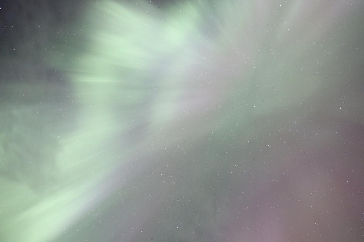 Photo looking straight up at bright white aurora.