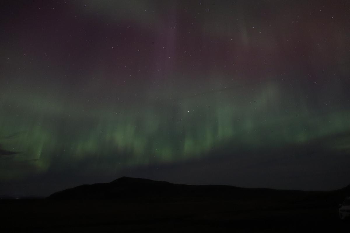 Photo of green aurora over mountains.