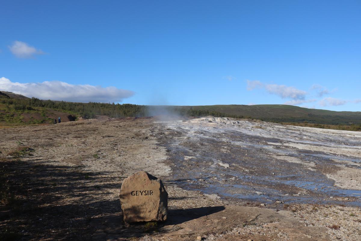 Photo of Geysir with a rock in front with its name engraved.