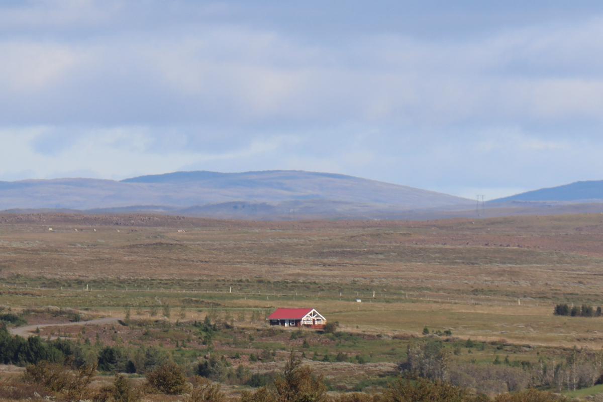 Photo of a house in the distance with a red roof.