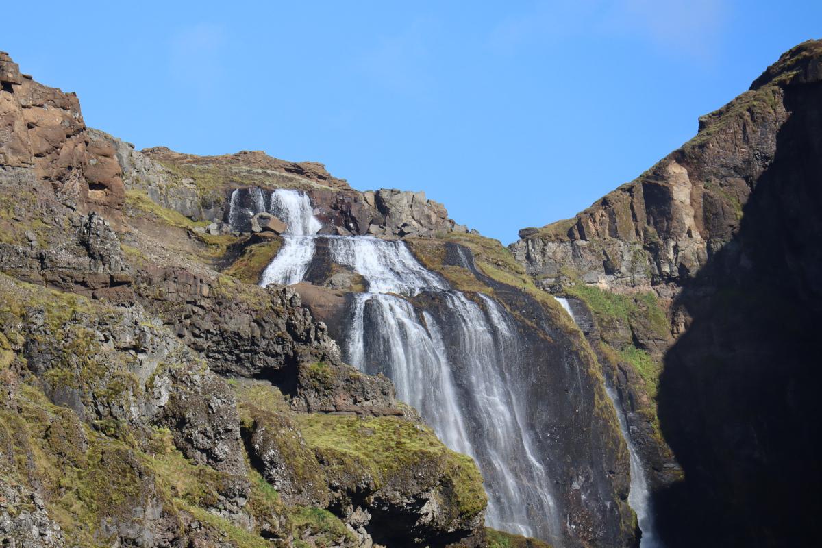 Photo looking up at waterfall, cascading down over multiple tiers of rock.