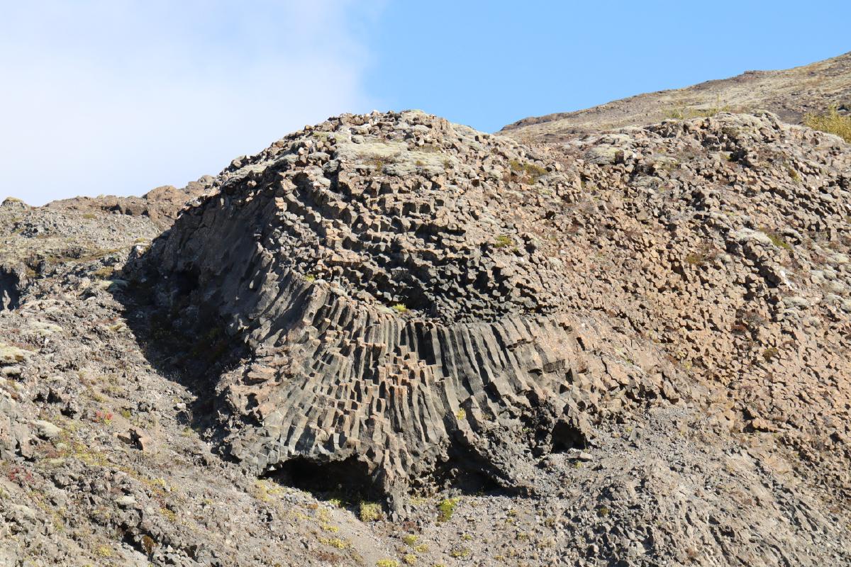 Photo of curved basalt columns on a hill.