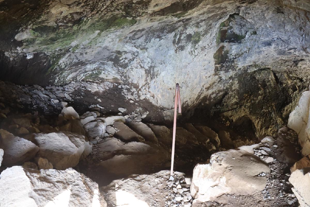 Photo of stone steps descending into a small, dark cave.