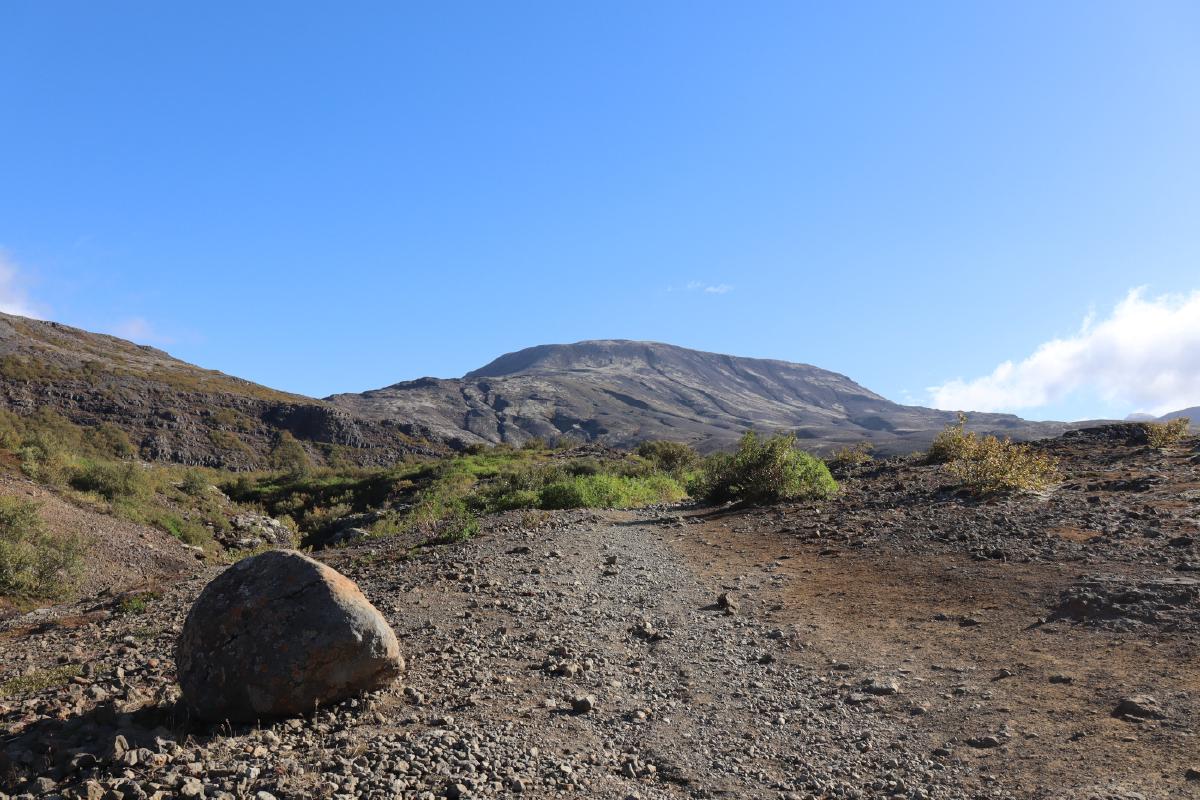 Photo of gravel trail leading towards a distant canyon.