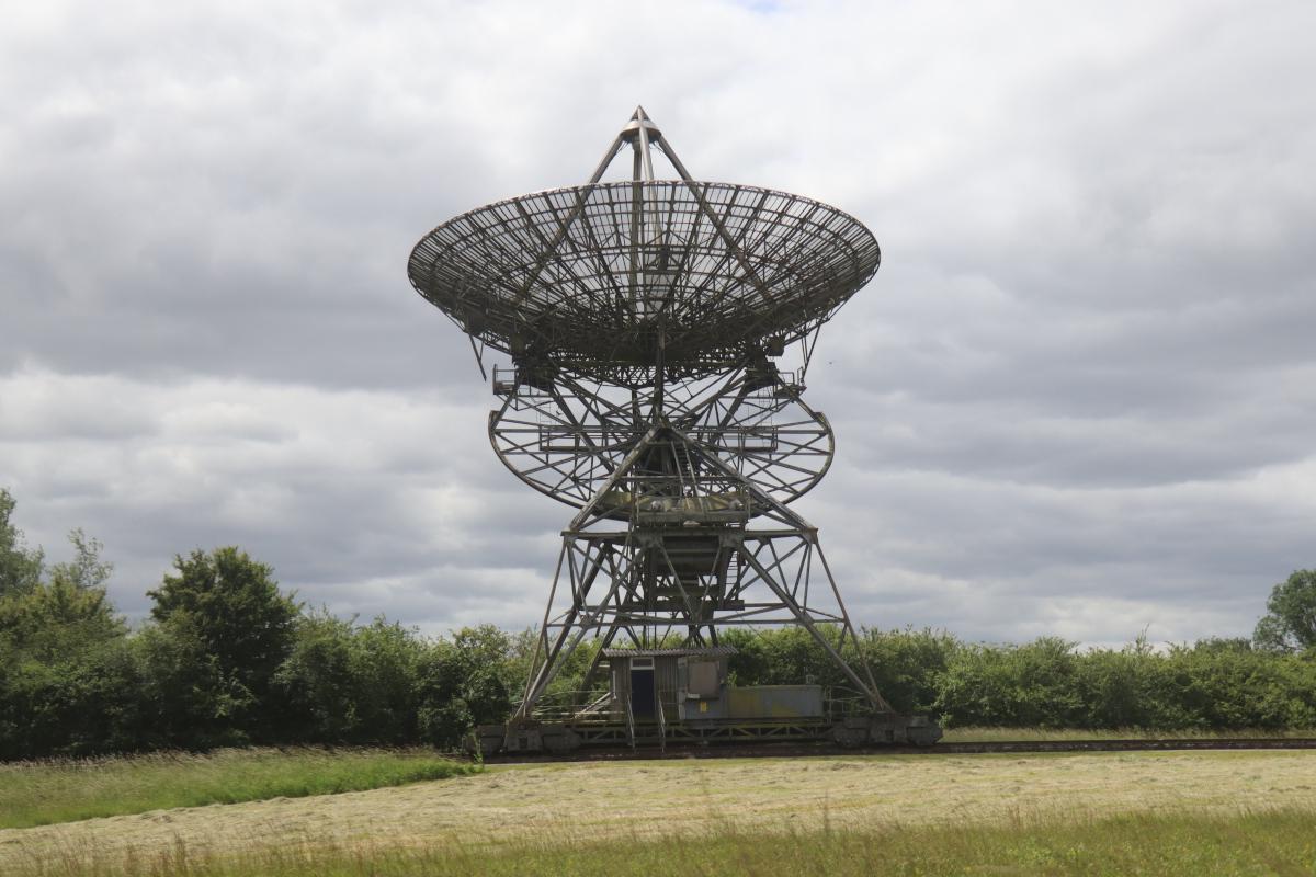 A side view of the track mounted One-Mile Telescope. It looks like a corrugated shack on wheels with a large dish above.