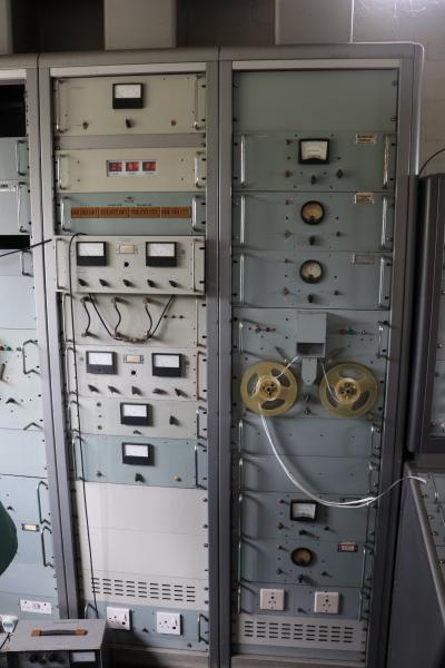 Several old equipment racks, with dials and a large casette.
