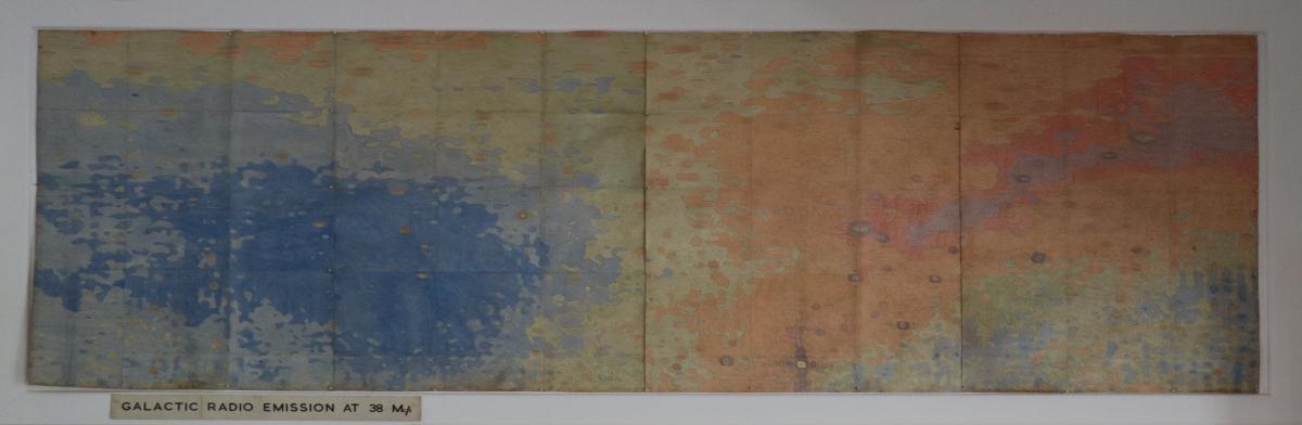 A wide, old poster, with speckled hues of blue, orange and red.