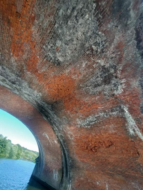 Looking up at the brick pattern of the railway bridge.