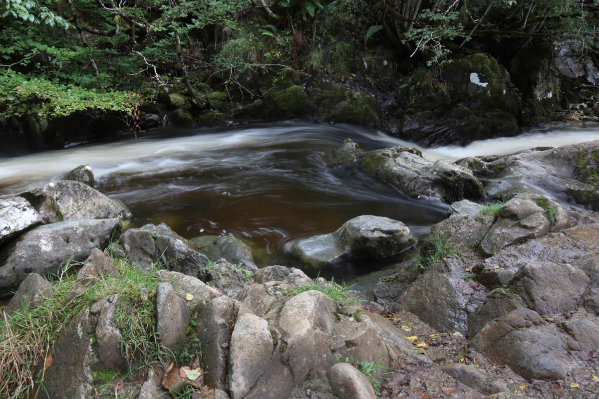 Long exposure of flowing water around rocks.