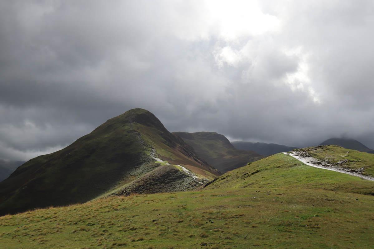A path along a shallow ridge top weaving towards a summit.