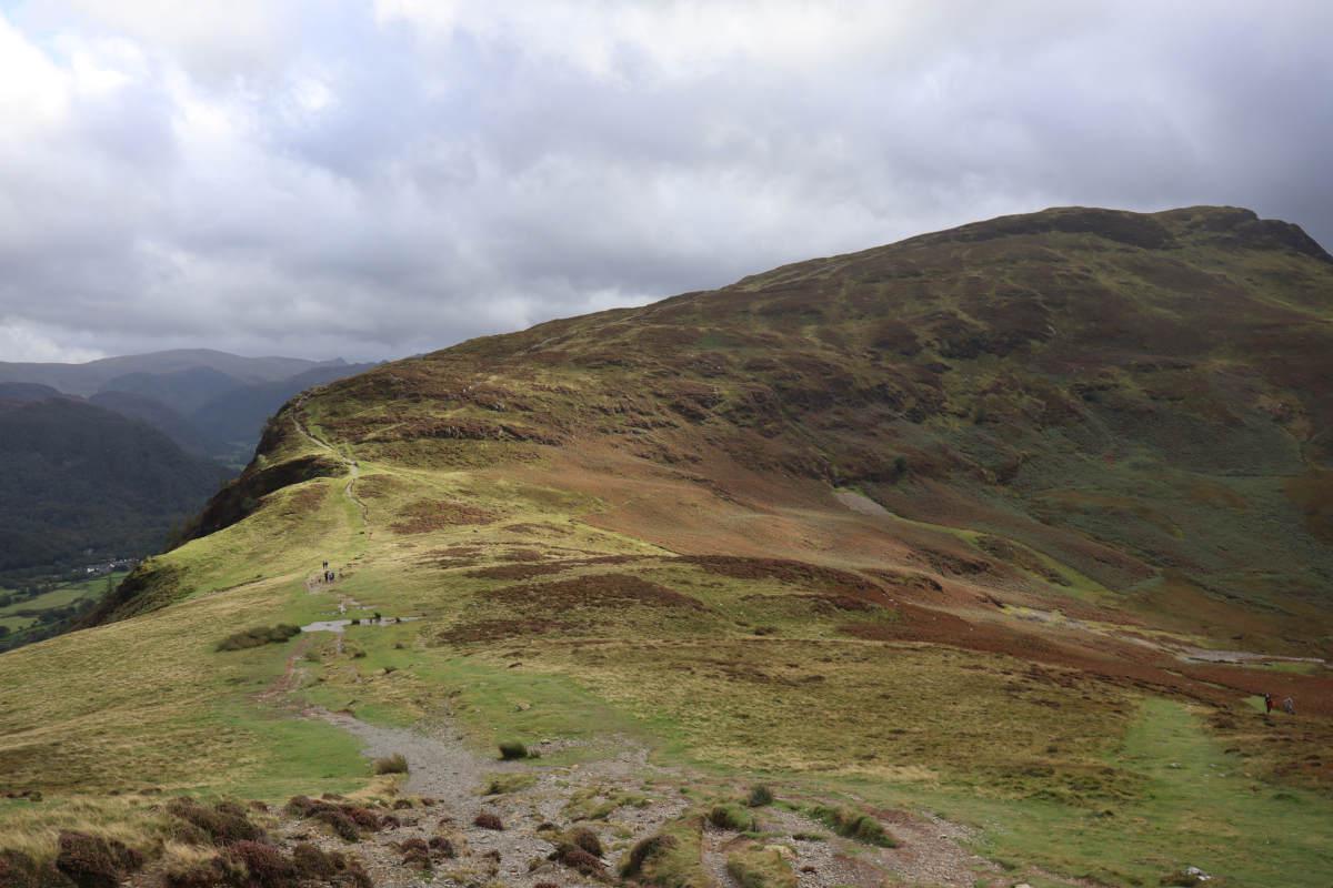 Sprawling hillside with a tiny cave in the distance.