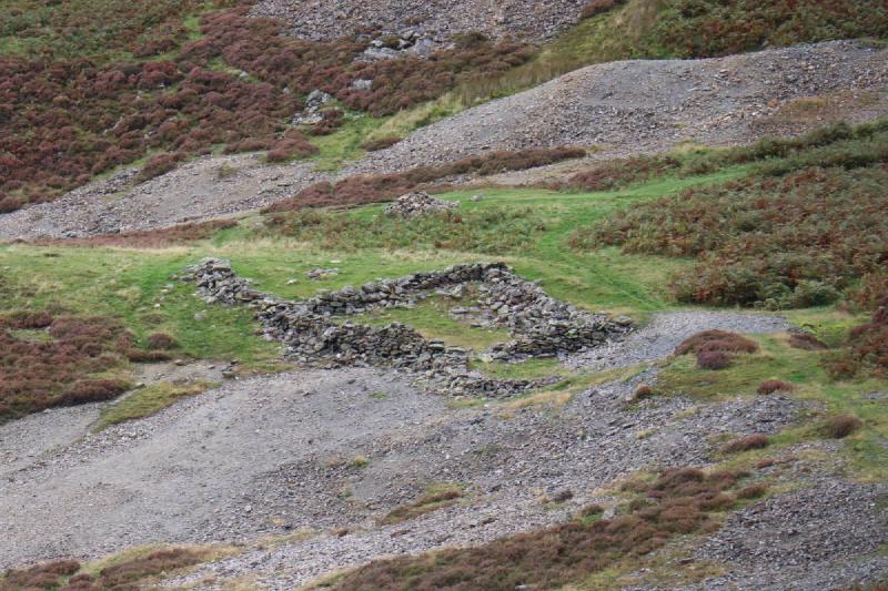 The outline of an old building marked by a low wall of stones.