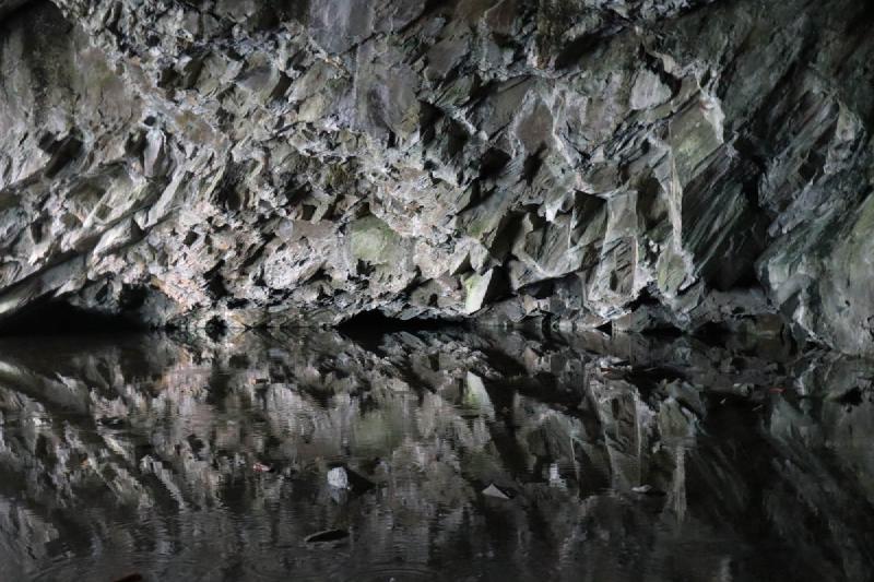 A jagged cave edge reflected in a calm pool.