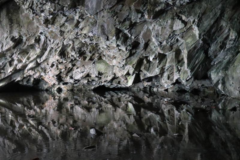 A jagged cave edge reflected in a calm pool.