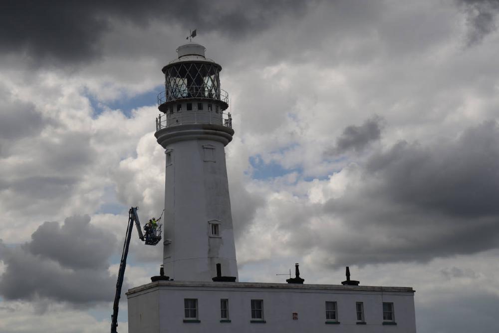 Men up a platform cleaning the lighthouse.