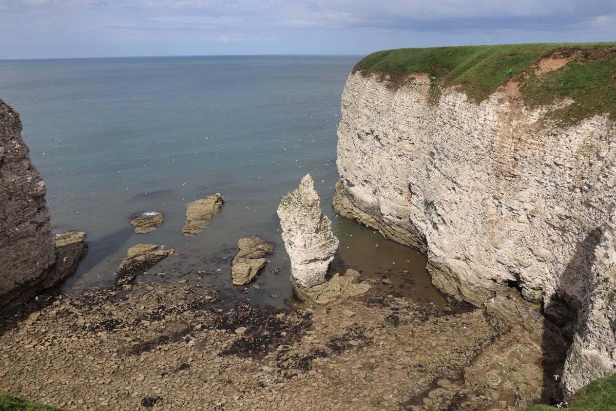 A single rock stack in the middle of a large bay.